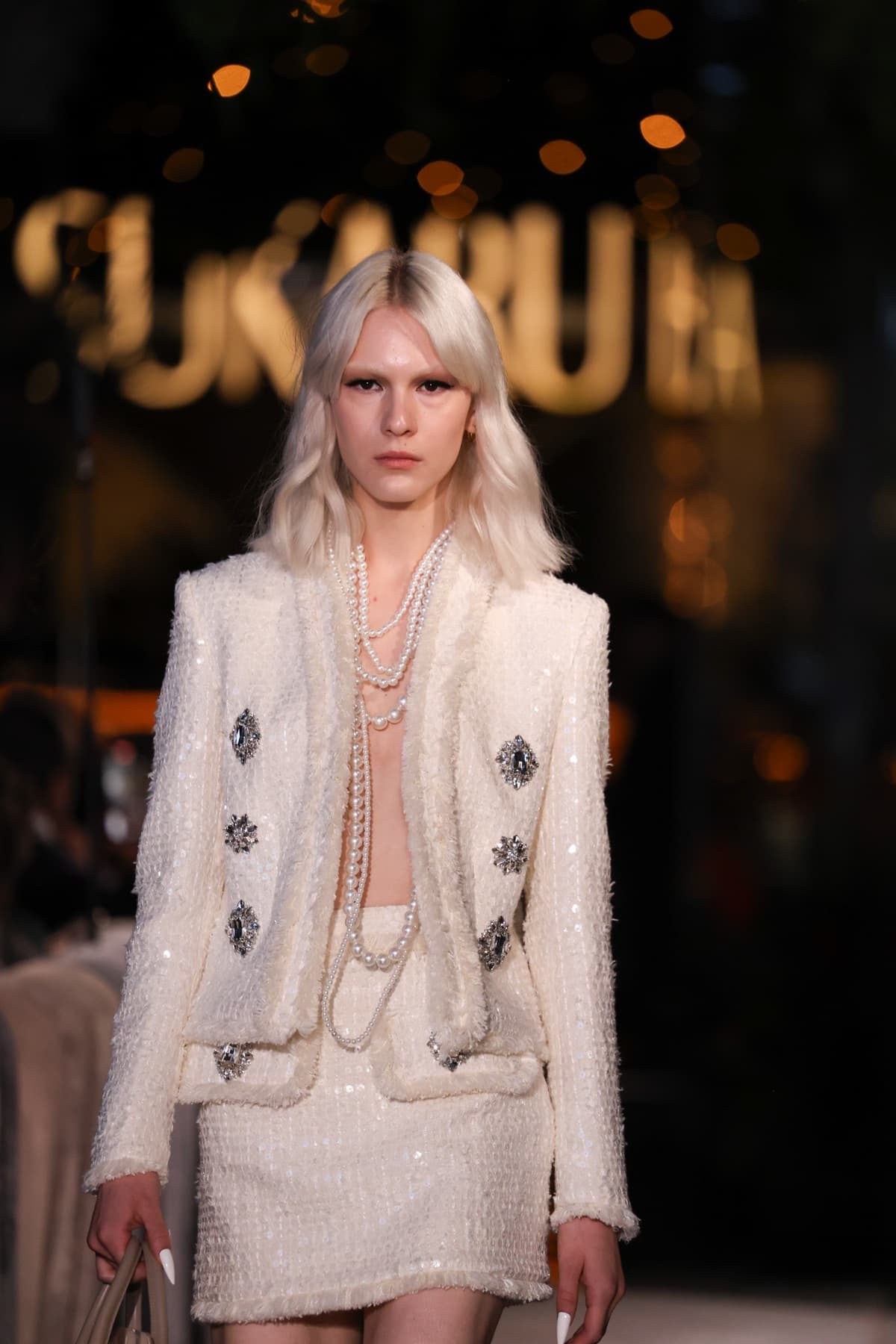 Cream tweed jacket and skirt layered with pearl ropes