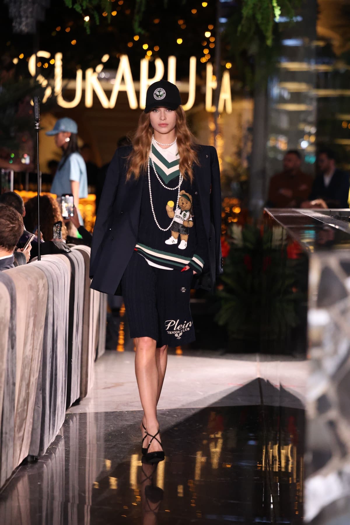 Navy blazer over a teddy bear knit, styled with a baseball cap and pearls